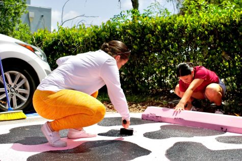 Using a small paint roller, Celine Mili paints on the black spots for her cow themed parking spot which also matches her phone case. 