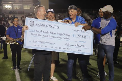 Band director Scott Davis receiving the check from commissioner Kionne McGhee.