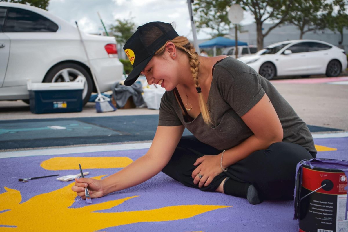 Senior Alixandra Ennis outlines the sun of her Tangled-inspired parking spot. 