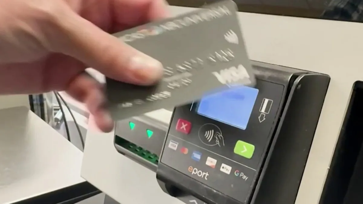 Person using a contactless tap to pay card reader at a checkout terminal